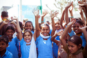 Sabbalpura, India - March 15, 2014: Group of indian school children - girls and boys wearing school uniforms posing in the rural village with raised hands, Rajasthan, India.
